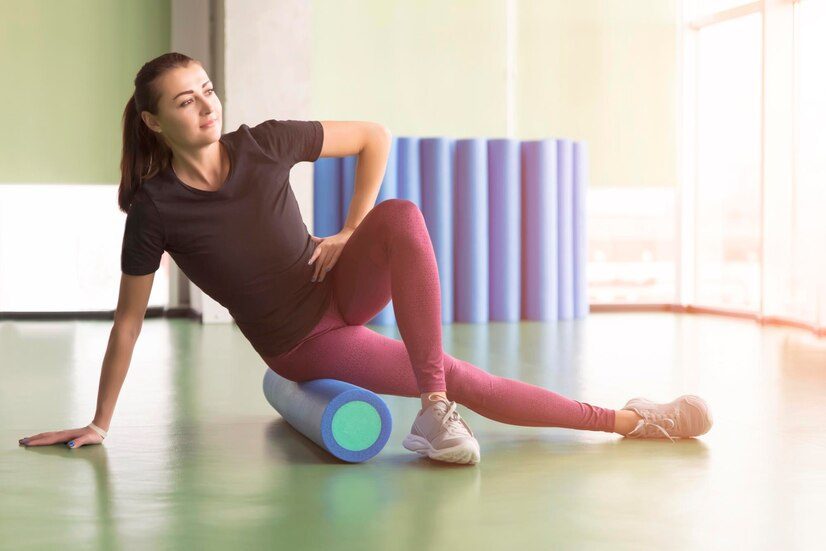 Rouleau pilates exercices : une femme fait un exercice de pilates avec un rouleau